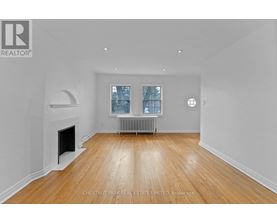 A spacious room with a fireplace and wooden flooring.