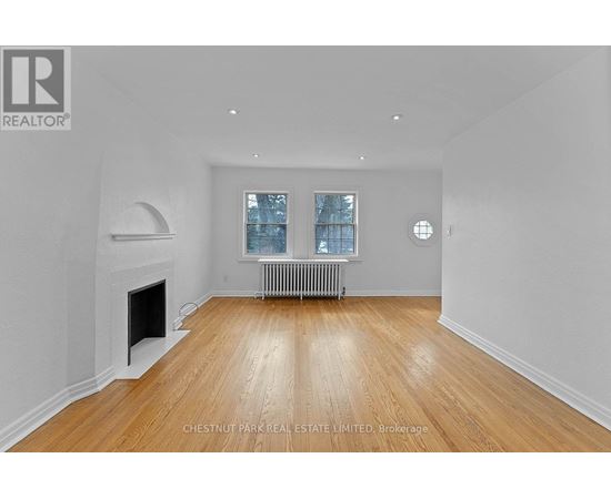 A spacious room with a fireplace and wooden flooring.