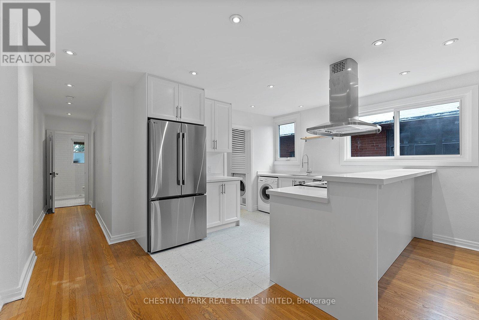 A modern kitchen with stainless steel appliances and wooden floors.