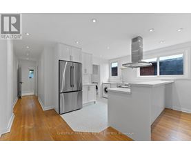 A modern kitchen with stainless steel appliances and wooden floors.