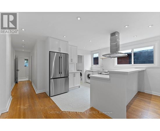 A modern kitchen with stainless steel appliances and wooden floors.