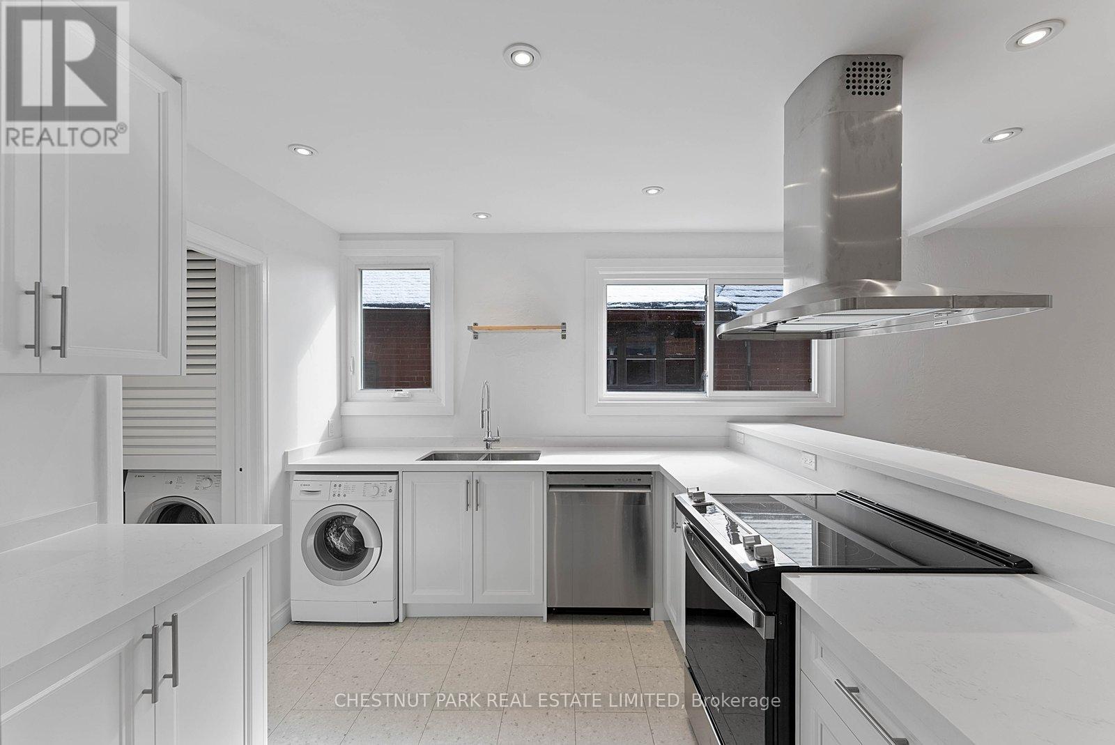 A modern kitchen with white cabinets and stainless steel appliances.