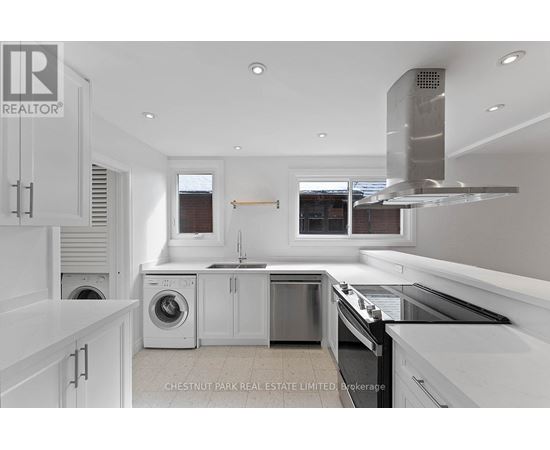A modern kitchen with white cabinets and stainless steel appliances.