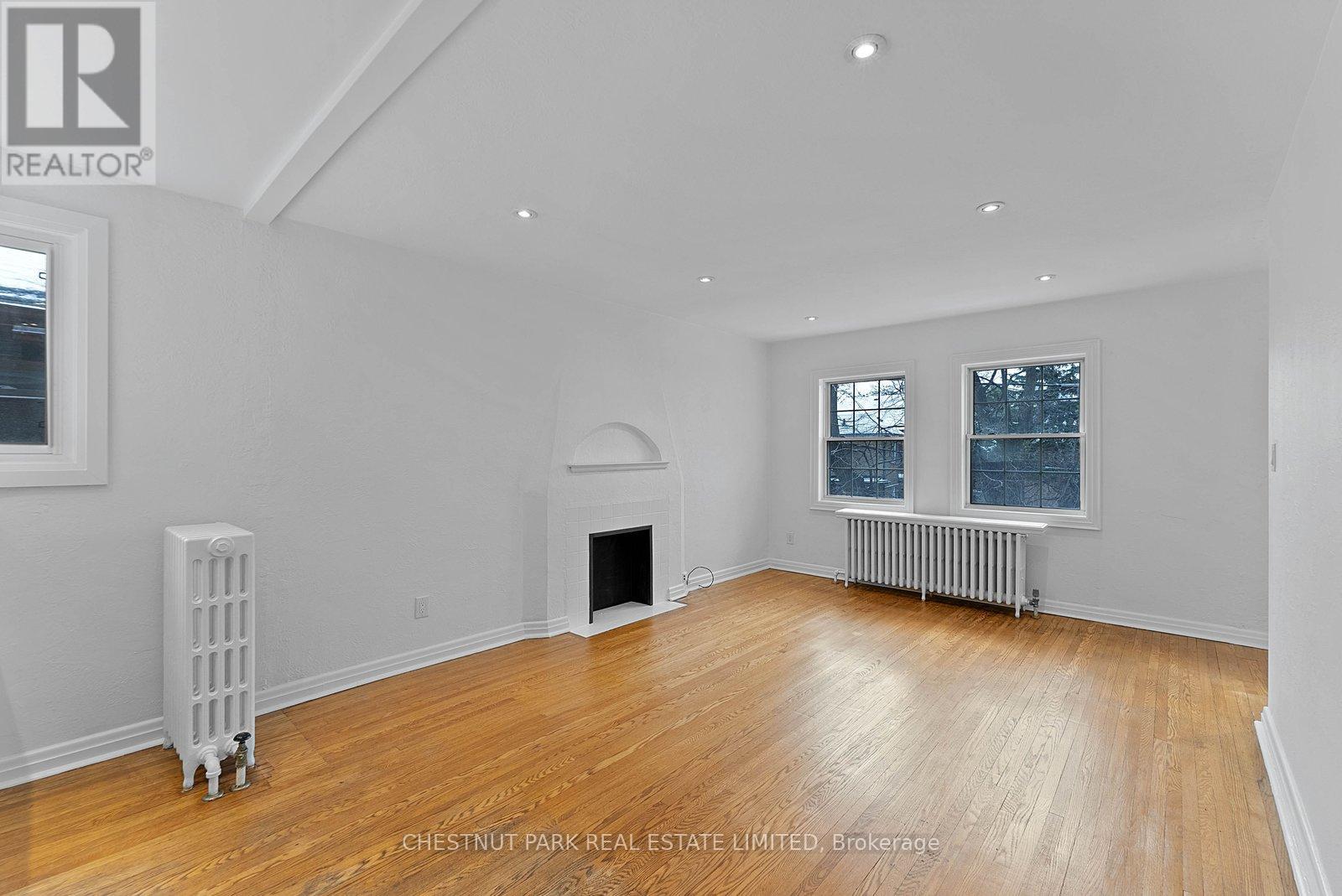 A spacious living room with wood flooring and white walls.