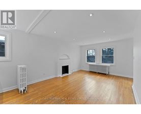 A spacious living room with wood flooring and white walls.