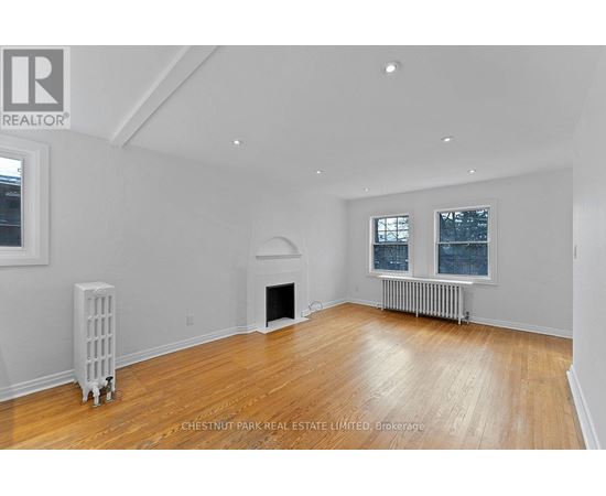 A spacious living room with wood flooring and white walls.