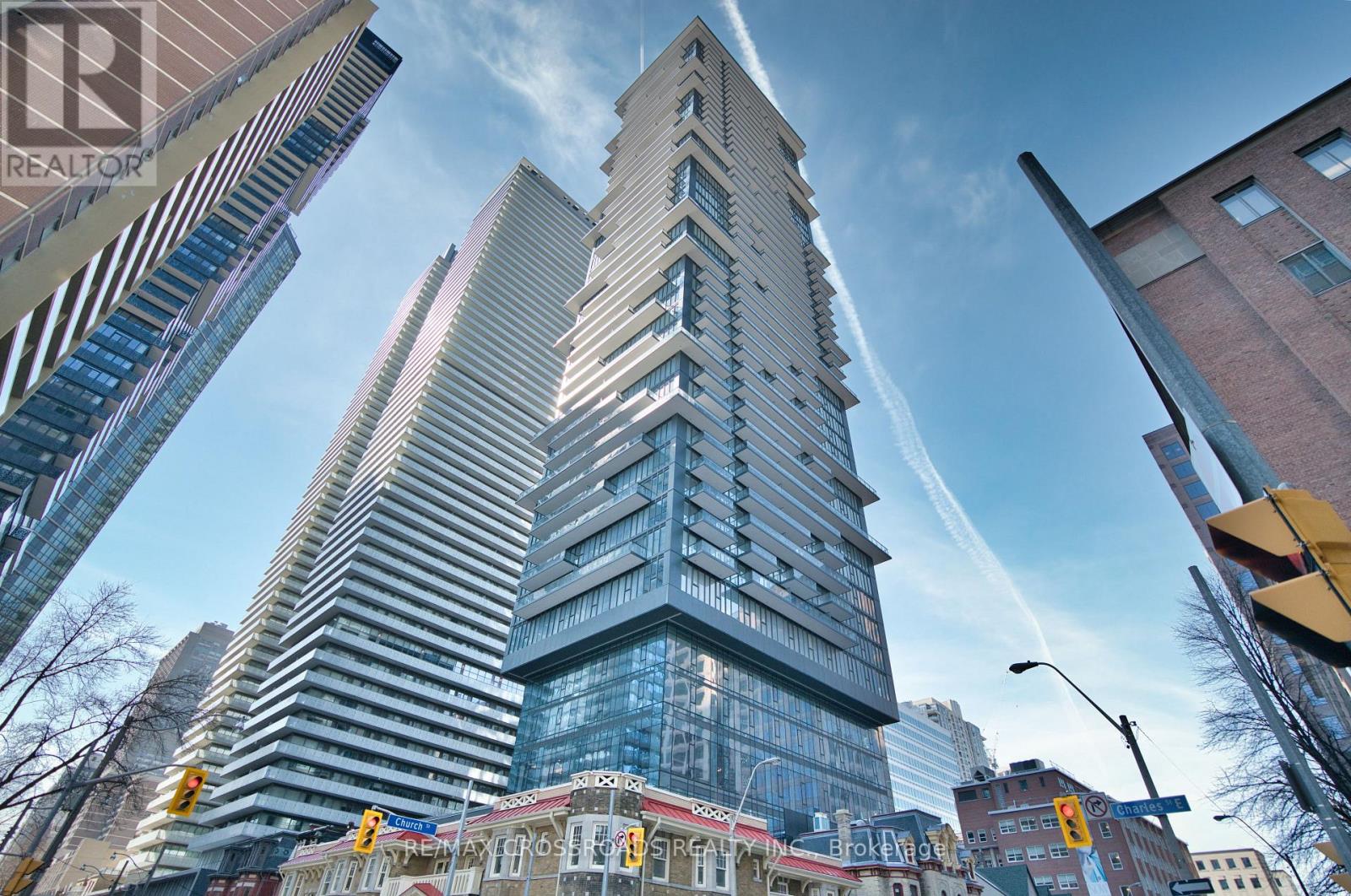 A tall building with a glass facade stands in the middle of a city street.