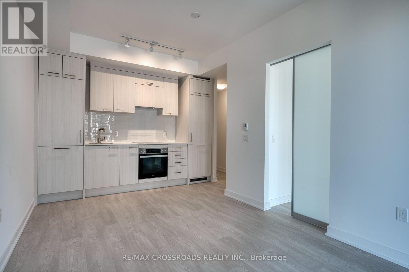 A modern kitchen with white cabinets and a wooden floor.