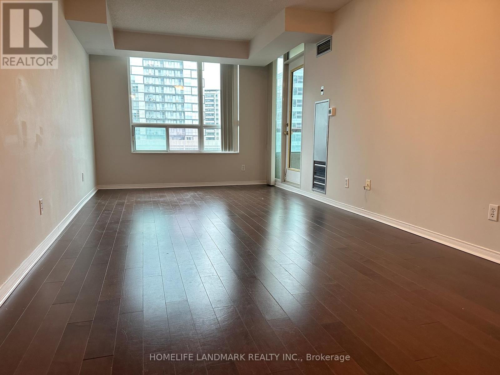 A room with wooden flooring and a large window.