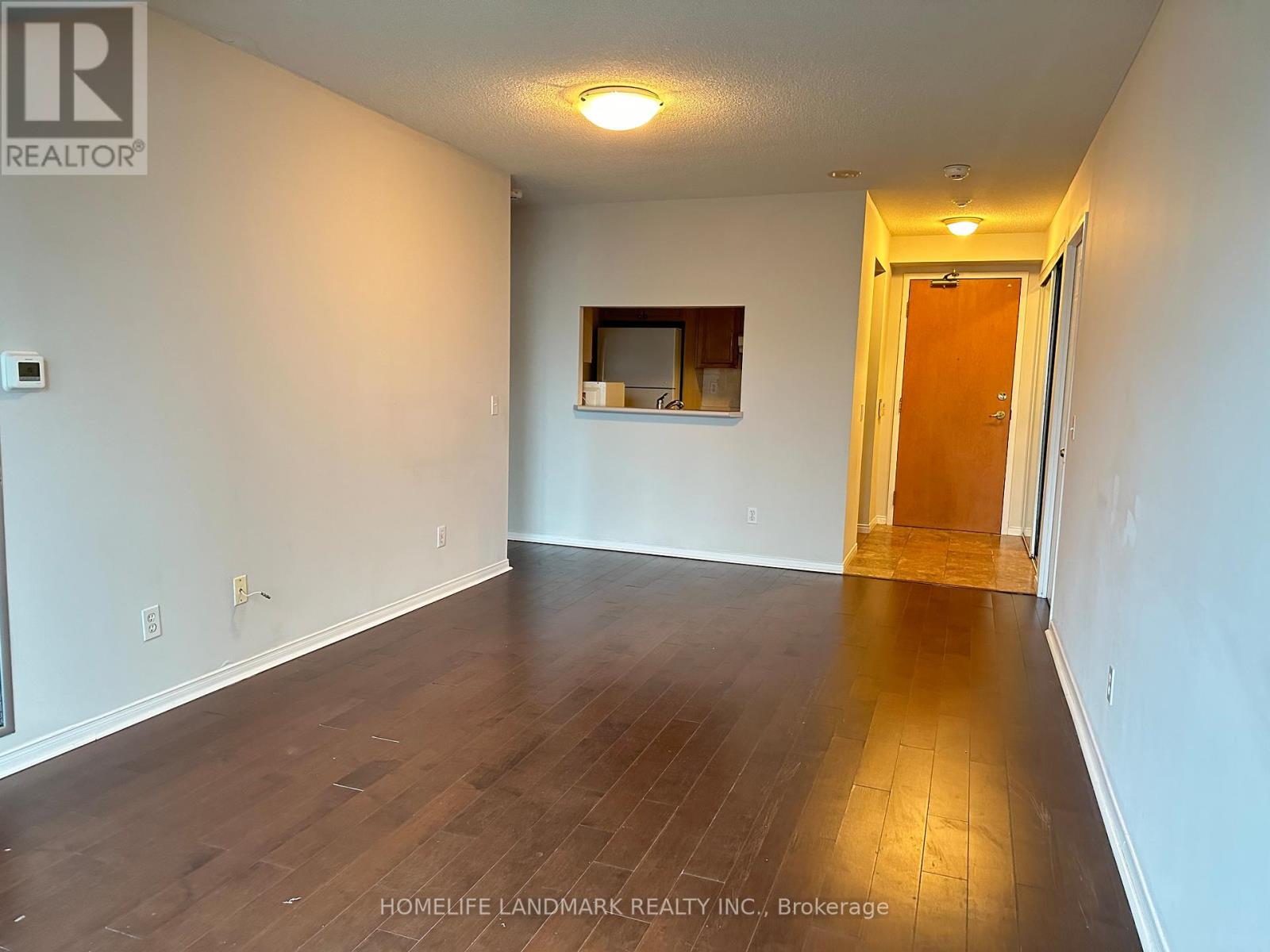 A room with wooden flooring and a door leading to another room.
