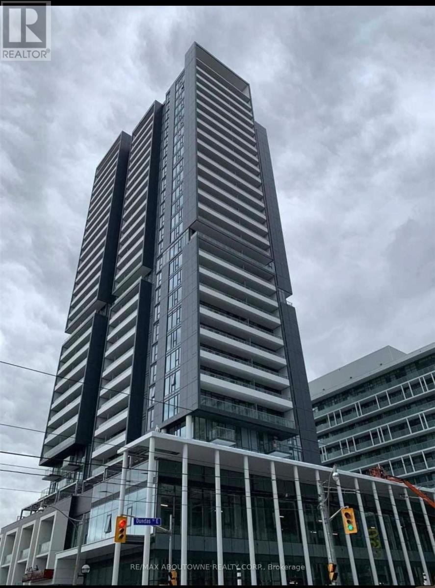A tall building with a glass facade stands under a cloudy sky.