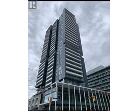 A tall building with a glass facade stands under a cloudy sky.