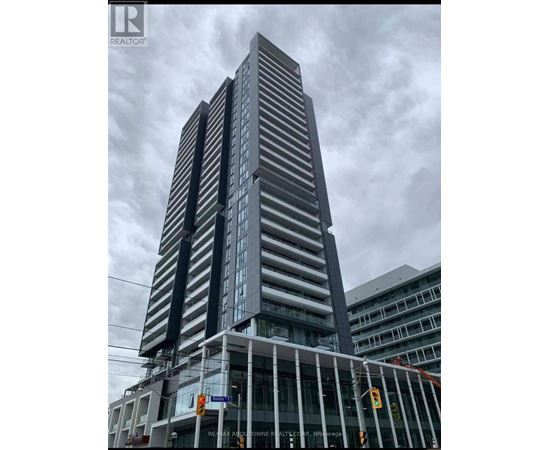 A tall building with a glass facade stands under a cloudy sky.