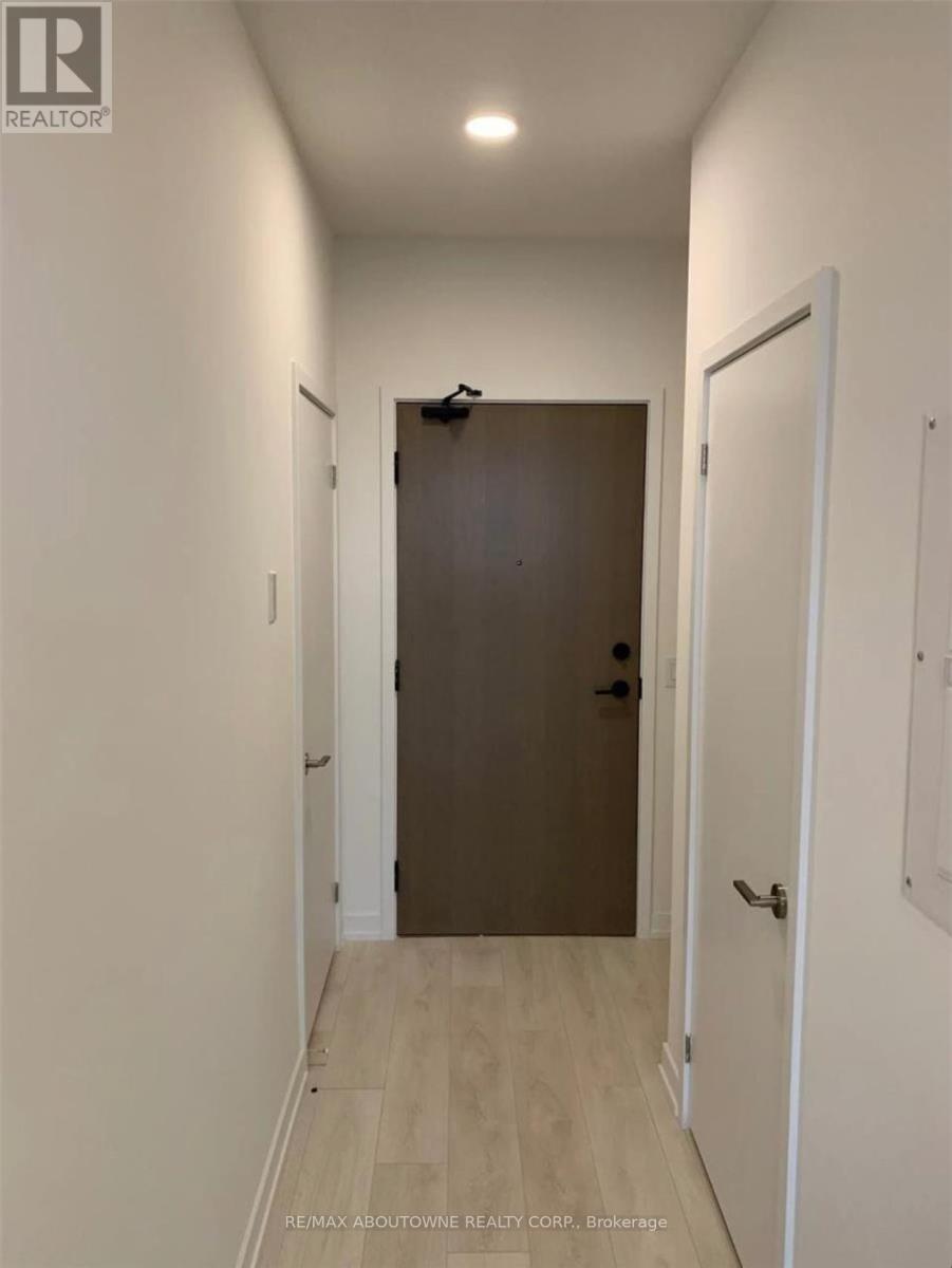 A hallway with a brown door and white walls.