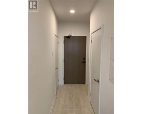 A hallway with a brown door and white walls.