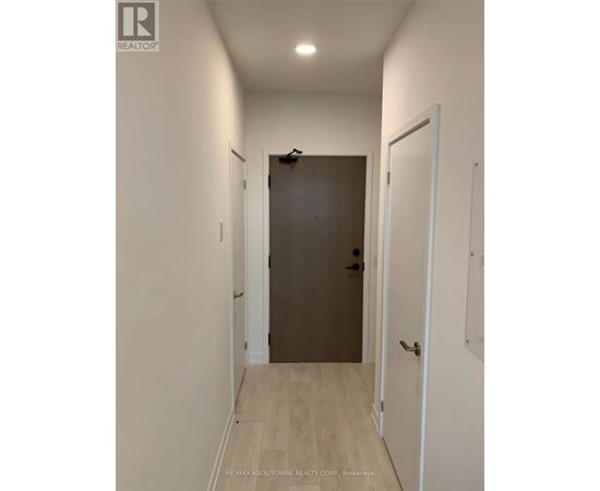 A hallway with a brown door and white walls.