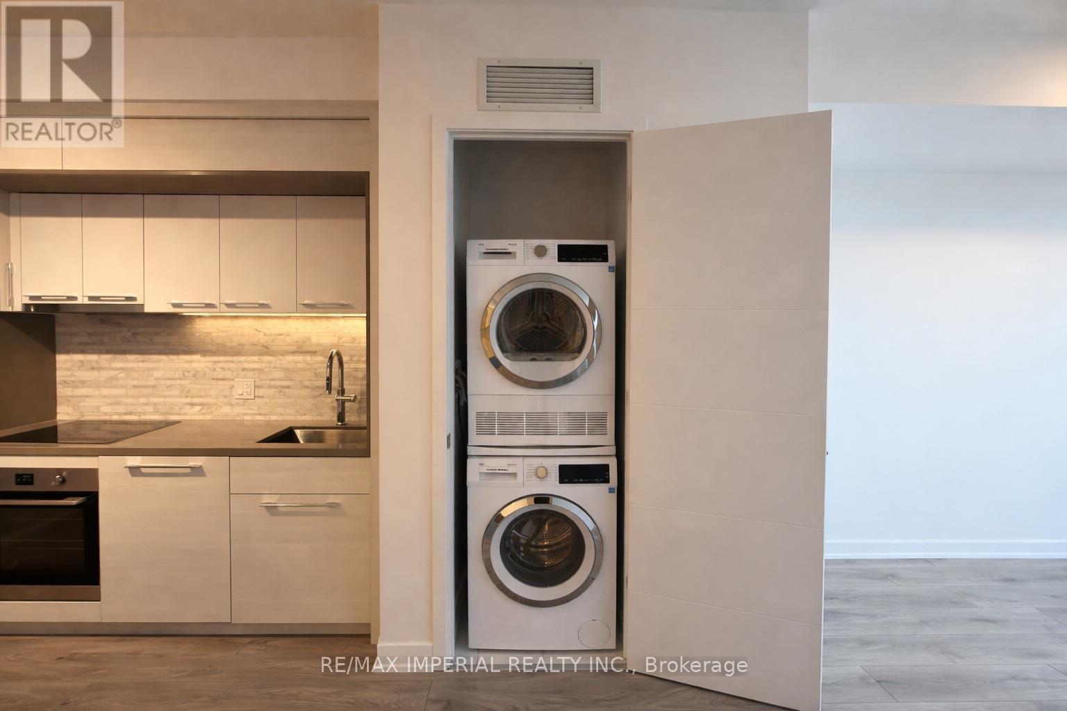 A washer and dryer are built into a wall in a modern kitchen.