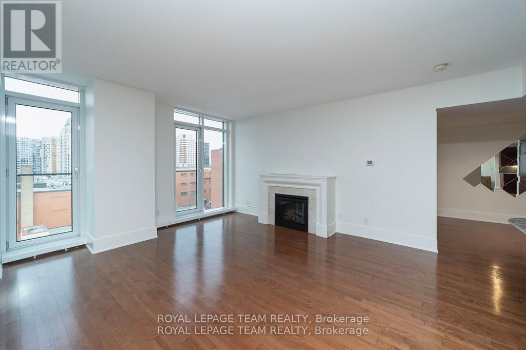 A spacious room with a fireplace and wood flooring.
