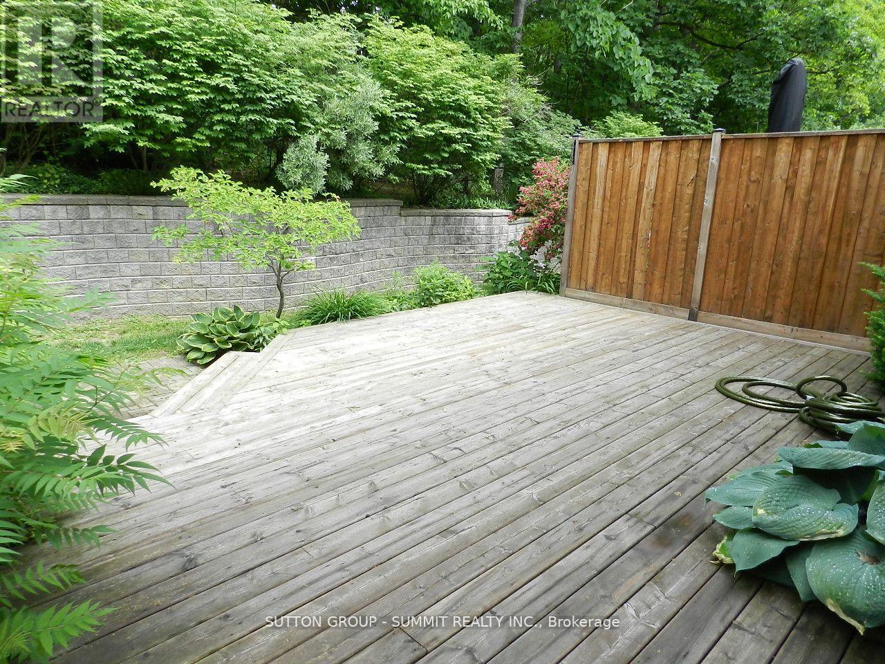 A wooden deck in a garden with a wall and a gate.