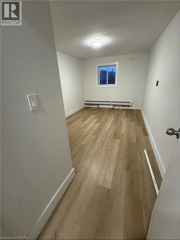 A room with wooden flooring and a window with a view of trees.