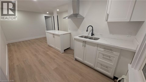 A kitchen with white cabinets and a wooden floor.
