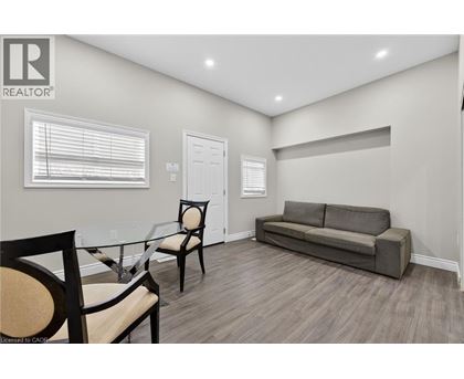 A living room with a grey couch, a glass table and two chairs.