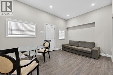 A living room with a grey couch, a glass table and two chairs.