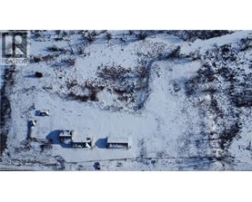A snowy landscape with a few buildings and a road.