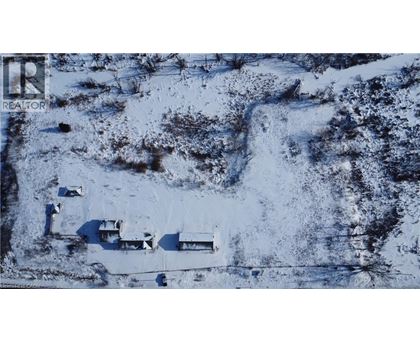 A snowy landscape with a few buildings and a road.