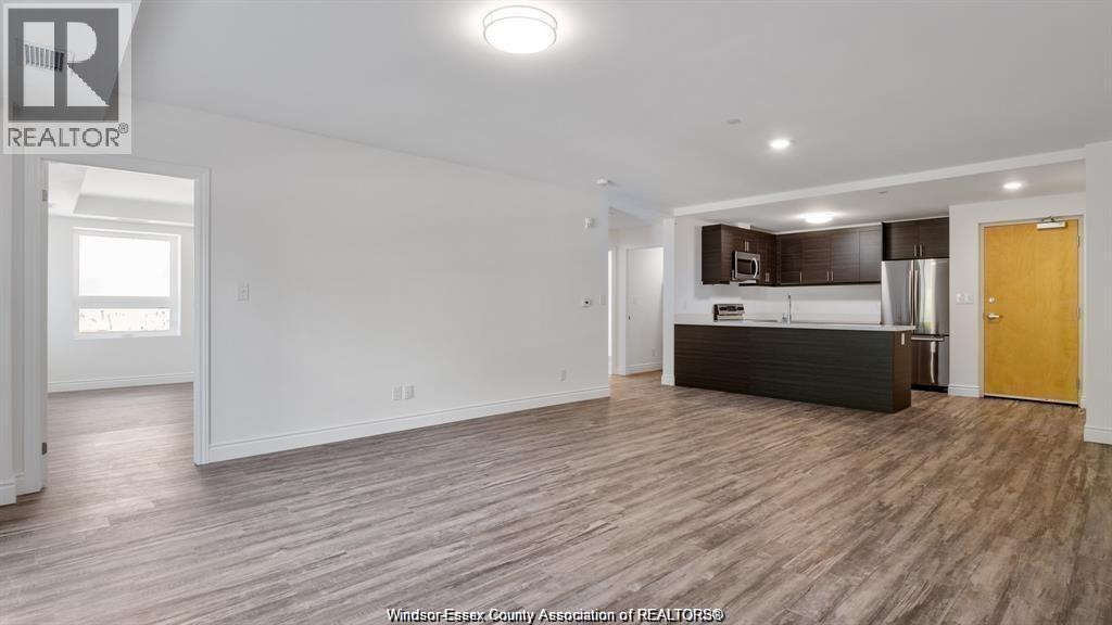 A spacious living room with a kitchenette in the background.