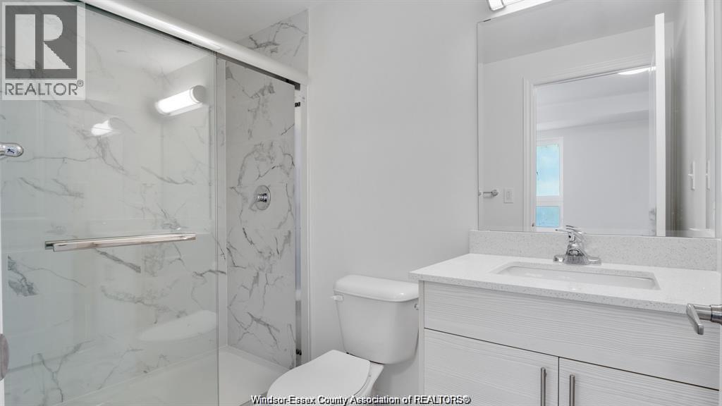 A white bathroom with a marble shower and toilet.