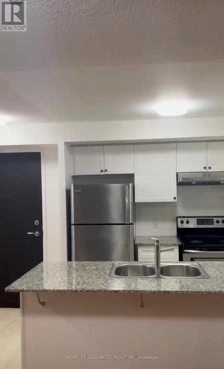 A kitchen with a stainless steel refrigerator and a granite countertop.