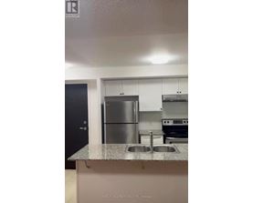 A kitchen with a stainless steel refrigerator and a granite countertop.