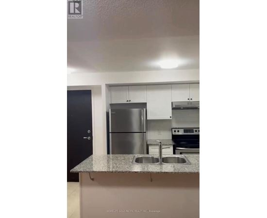 A kitchen with a stainless steel refrigerator and a granite countertop.