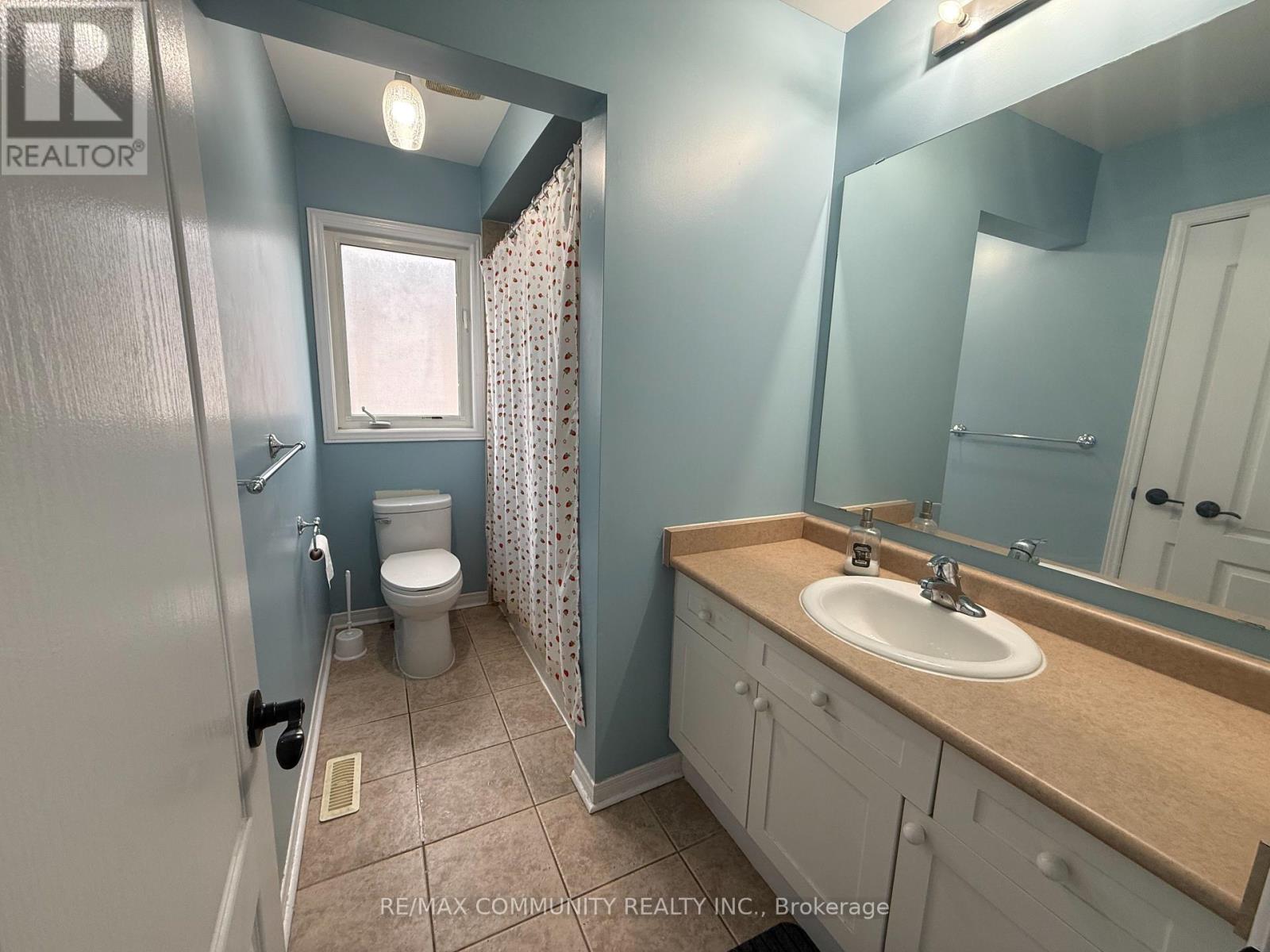 A bathroom with a toilet, sink, and mirror.