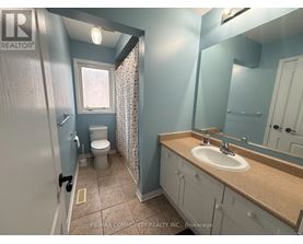 A bathroom with a toilet, sink, and mirror.