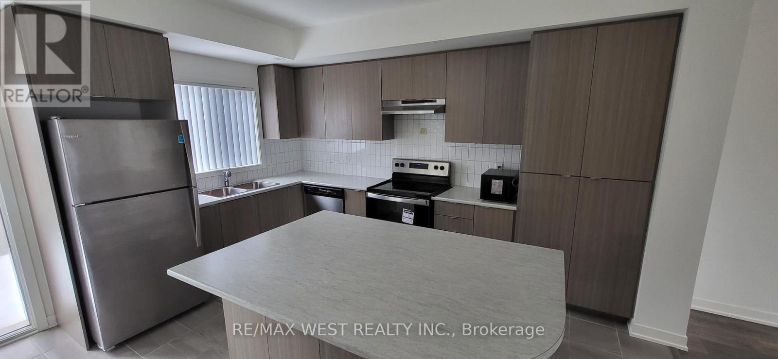 A kitchen with a refrigerator, oven, and microwave.
