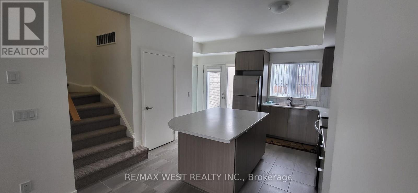 A kitchen area with a counter and stairs leading to the upper floor.