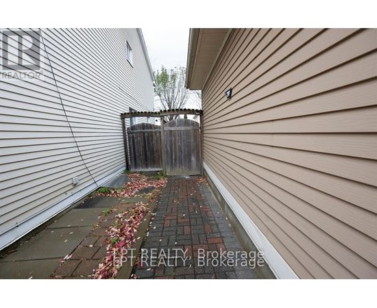 A narrow alley with a wooden fence and a brick path.