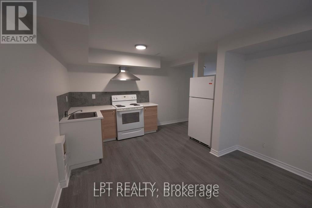 A kitchen with a refrigerator, oven, and sink.