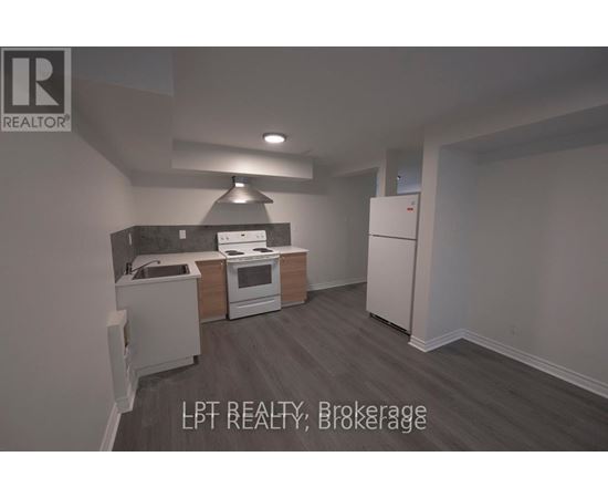 A kitchen with a refrigerator, oven, and sink.
