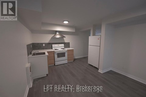 A kitchen with a refrigerator, oven, and sink.