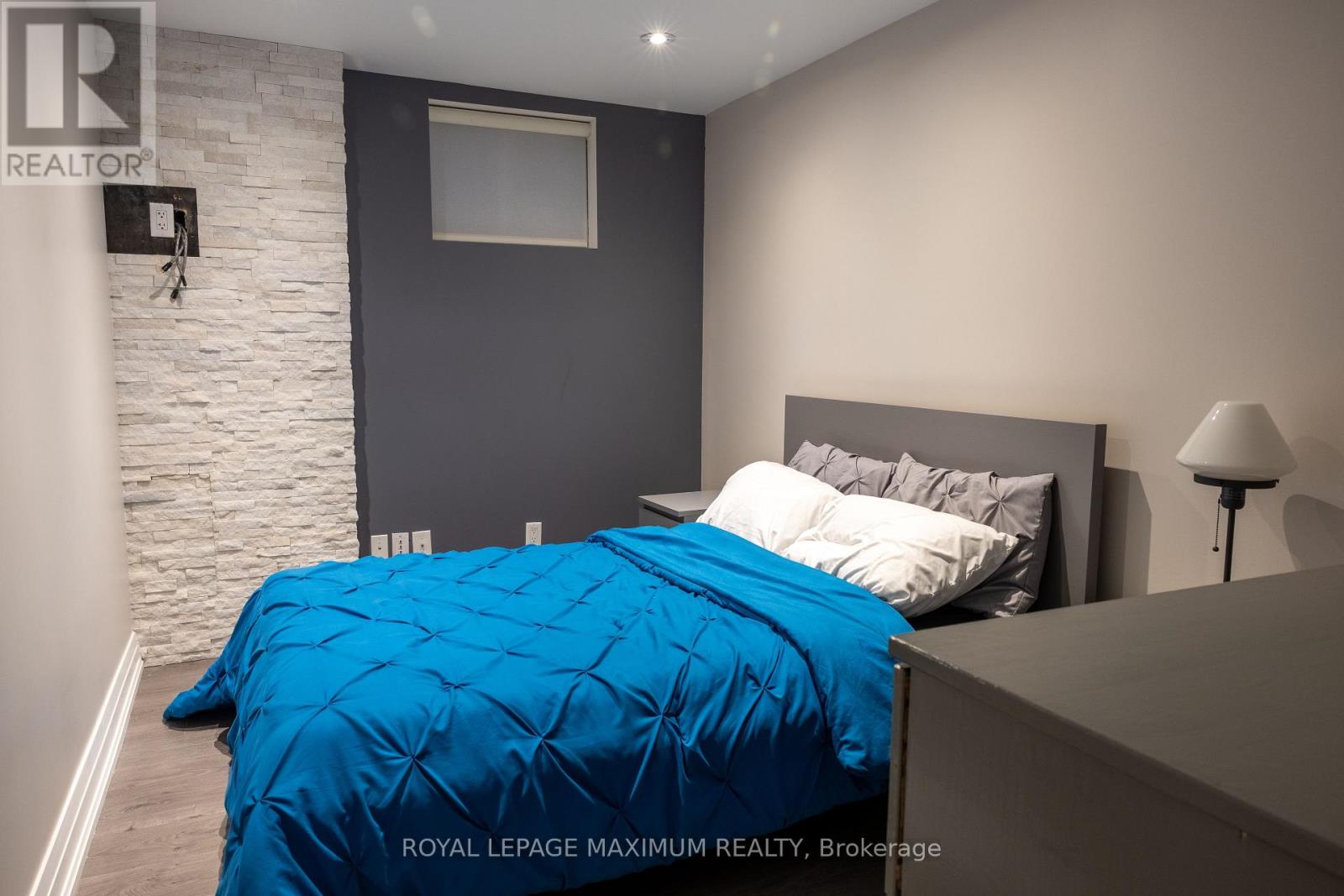 A bedroom with a blue bedspread and a white bed.