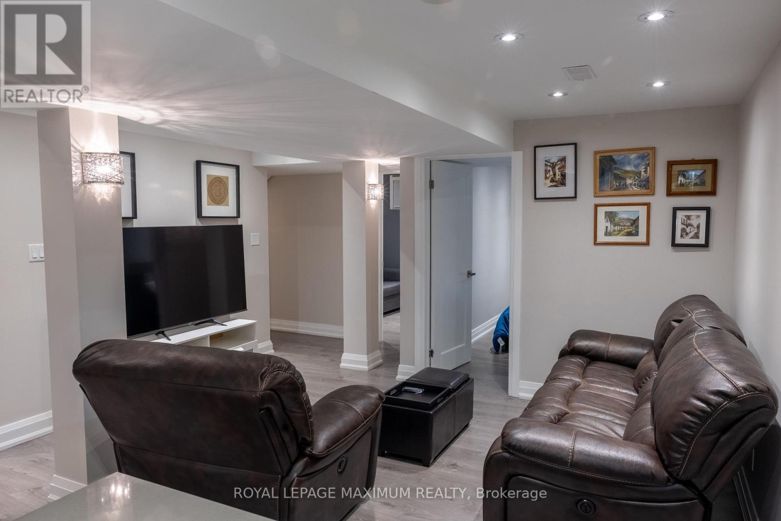 A living room with a brown leather couch and a black television.