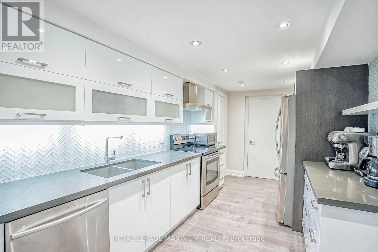 A modern kitchen with white cabinets and stainless steel appliances.
