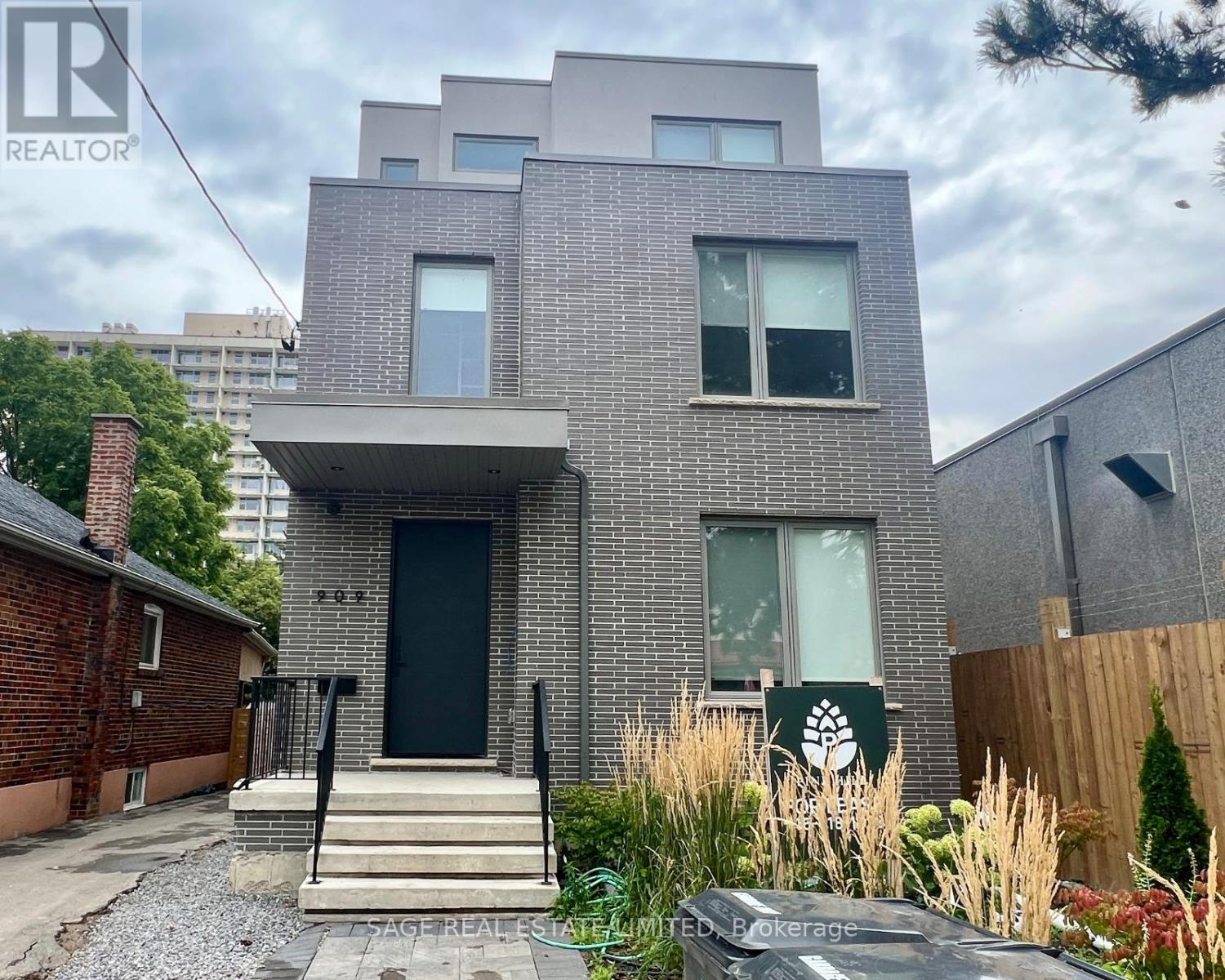 A grey brick house with a black door and windows.