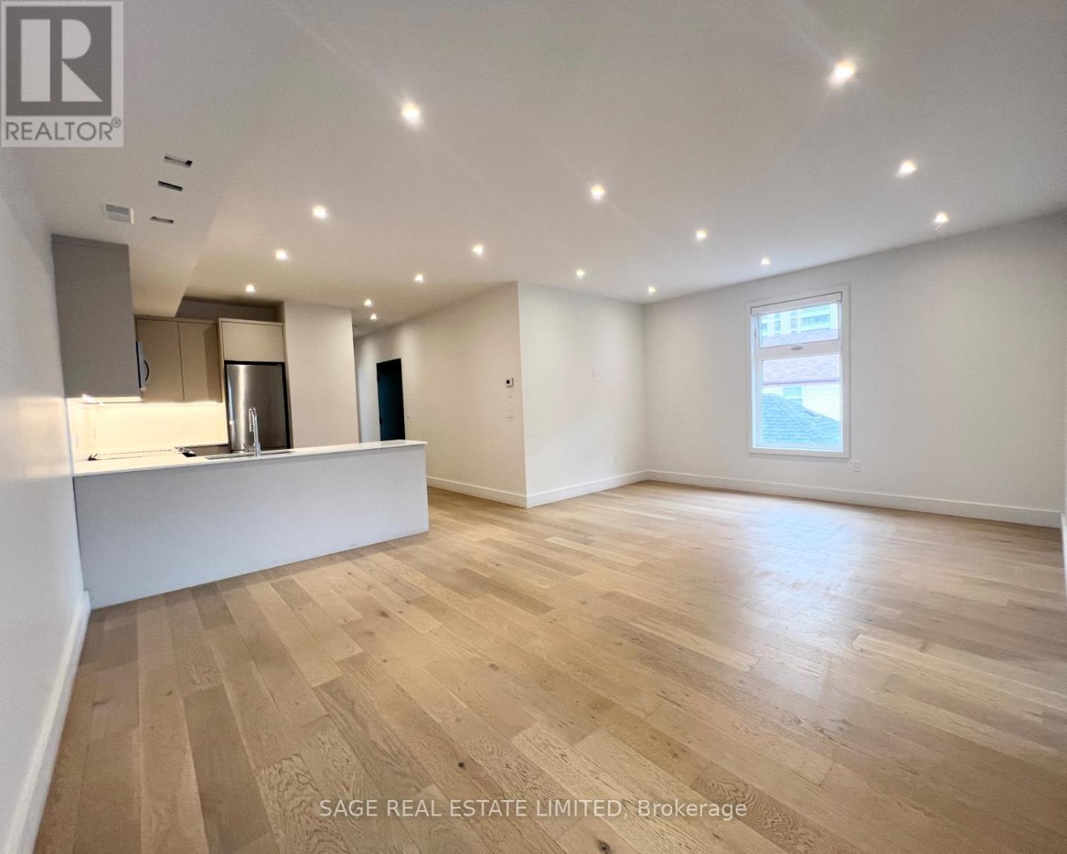 A spacious room with wooden flooring and a large window.