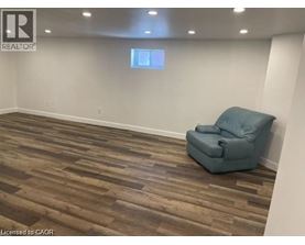 A room with a blue chair and wooden flooring.