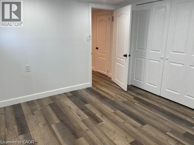 A room with a wooden floor and white walls, with a doorway leading to another room.