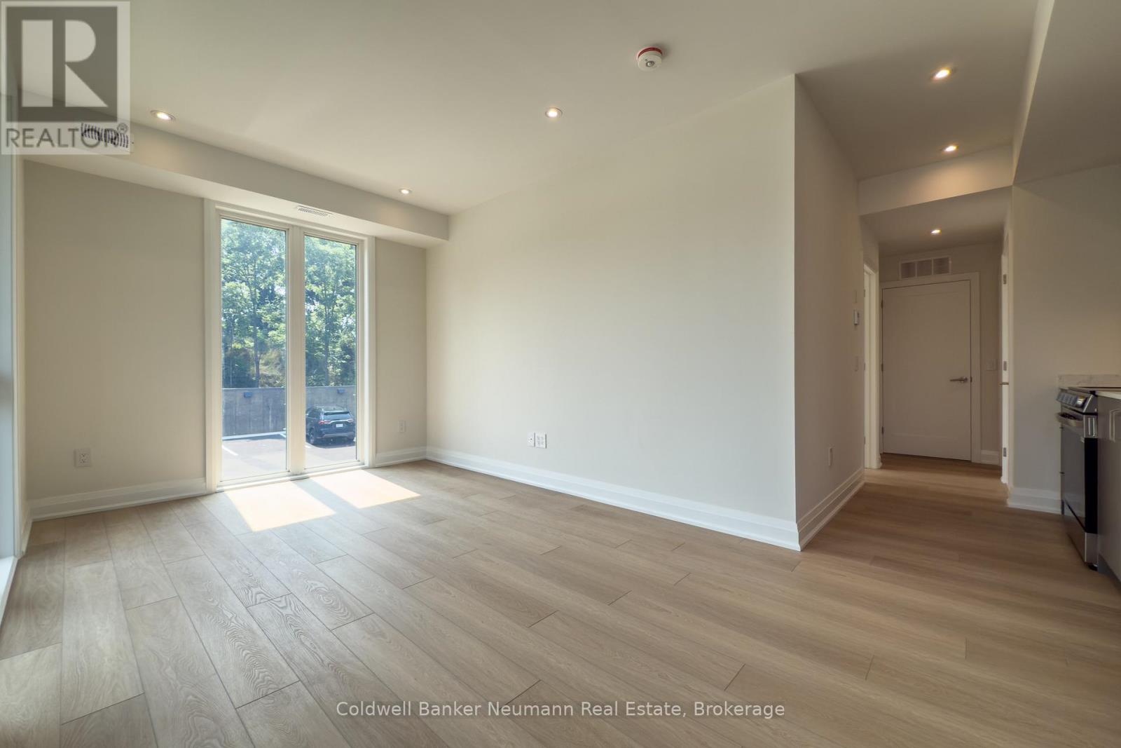 A spacious room with wooden flooring and a large window.